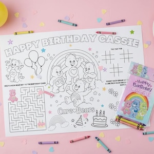 Op de afbeelding: Een witte kleurplaat met de tekst "HAPPY BIRTHDAY CASSIE" en Care Bears-illustraties. Bevat een doolhof, boter-kaas-en-eieren en een kleurpotlodenset met de tekst "Happy Birthday Cassie". Kleurpotloden en confetti zijn verspreid.