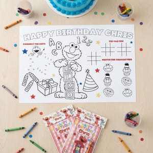 May include: A birthday party scene with a blue frosted cake, crayons, and a coloring placemat featuring Elmo. The placemat has the text "Happy Birthday Chris" and includes connect-the-dots, tic-tac-toe, and matching games. Two crayon packs are also visible.