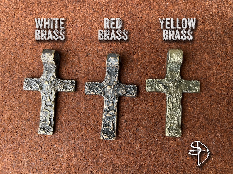 May include: Three ornate cross pendants in different finishes: white brass, red brass, and yellow brass. Each cross has a textured surface and a loop at the top for hanging.