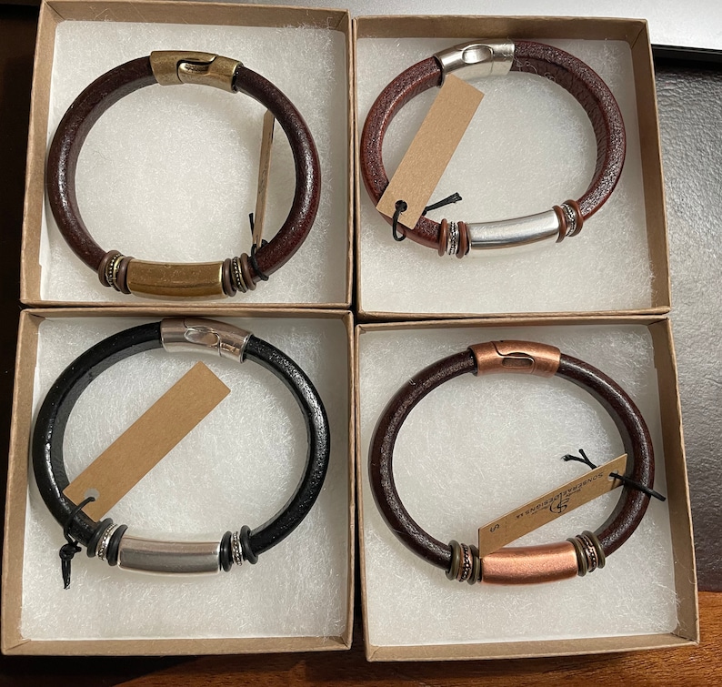 Pu&ograve; includere: Quattro braccialetti in pelle con dettagli in metallo. Ogni braccialetto &egrave; esposto in una scatola separata. I braccialetti sono di colore marrone, nero e marrone con dettagli in rame.