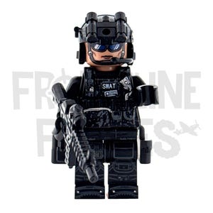 Op de afbeelding: Een zwart SWAT-team actiefiguur met helm, bril en headset. De figuur houdt een zwart geweer vast en draagt een tactisch vest met het woord "SWAT". De figuur is gemaakt van plastic.