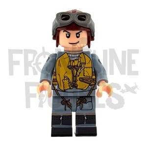 Pode incluir: Uma figura de Lego de um piloto usando um capacete cinza com óculos, um colete amarelo e um uniforme cinza. A figura tem uma expressão neutra e está em pé. O texto "FRONTLINE FIGURES" é visível no fundo.