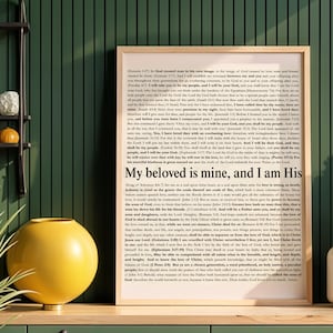 May include: A framed print with the text "My beloved is mine, and I am His" in a wooden frame. The print is displayed on a green surface with a yellow vase and decorative items.