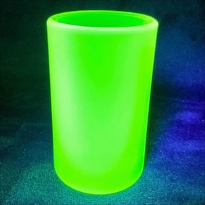 Può includere: Un bicchiere cilindrico verde neon. Il bicchiere ha una base liscia e arrotondata e un bordo leggermente svasato. Il colore verde brillante è uniforme, creando un effetto visivo sorprendente. Il bicchiere è probabilmente progettato per bevande.