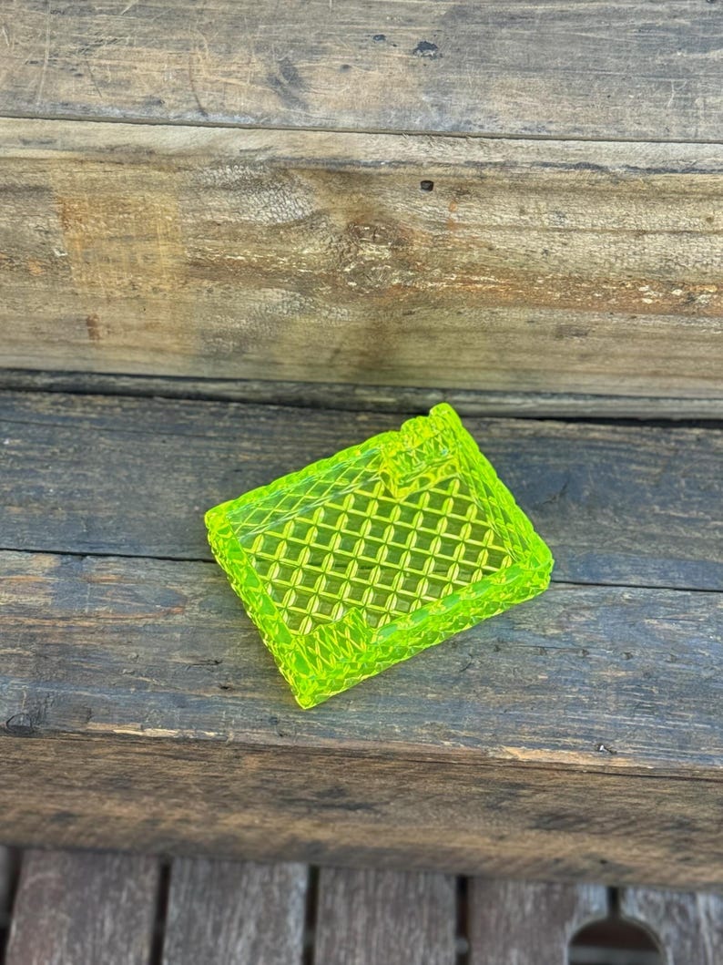 May include: A neon green, rectangular, decorative tray with a diamond pattern. The tray is made of a translucent material and sits on a weathered wooden surface.
