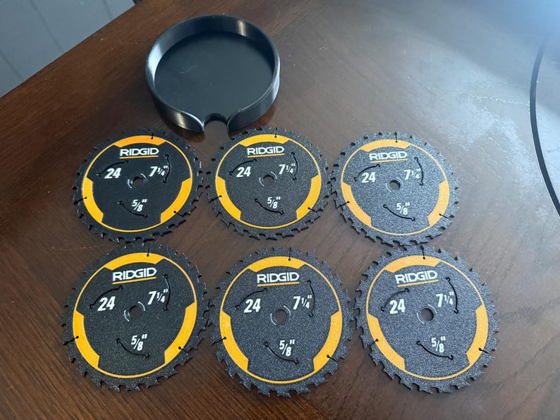 May include: A set of six black and yellow RIDGID circular saw blades with a black holder. Each blade has the text "RIDGID", "24", "7 1/4", and "5/8" printed on it. The blades are designed for cutting wood.
