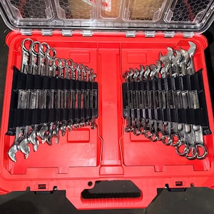 May include: A red toolbox with a clear lid, filled with a set of shiny, silver wrenches. The wrenches are organized in black holders, with various sizes visible. The toolbox is open, showcasing the tools.