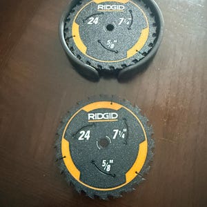 May include: Two black RIDGID circular saw blades with orange accents. Each blade has a 7 1/4 inch diameter, 5/8 inch arbor, and 24 teeth. One blade is in a black protective case.
