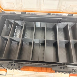 May include: Open black toolbox with an orange handle and clear lid. The interior is divided into multiple compartments of varying sizes. The toolbox is designed for organizing and storing tools and other small items. The lid is open, revealing the interior organization.