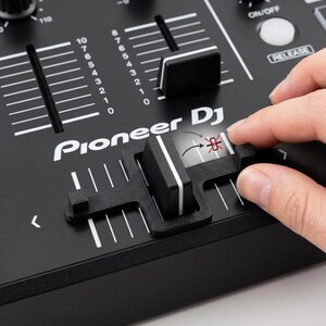 Könnte beinhalten: Ein schwarzes, 3D-gedrucktes Fader-Begrenzer-Zubehör aus Kunststoff, das an einem Pioneer DJ-Mixer befestigt ist. Das Gerät verfügt über einen rechteckigen Rahmen, der über den zentralen Fader-Knopf passt und dessen Bewegungsbereich einschränkt.