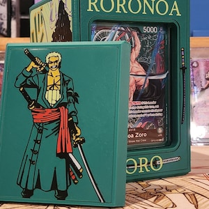 May include: Green card holder featuring the name "RORONOA" and a graphic of a character with swords. The holder contains a card with the character "Roronoa Zoro" and the number "5000". The holder is displayed with other card holders.