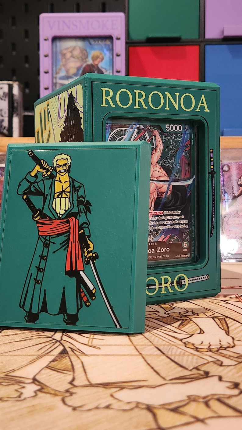 May include: Green card holder featuring the name "RORONOA" and a graphic of a character with swords. The holder contains a card with the character "Roronoa Zoro" and the number "5000". The holder is displayed with other card holders.
