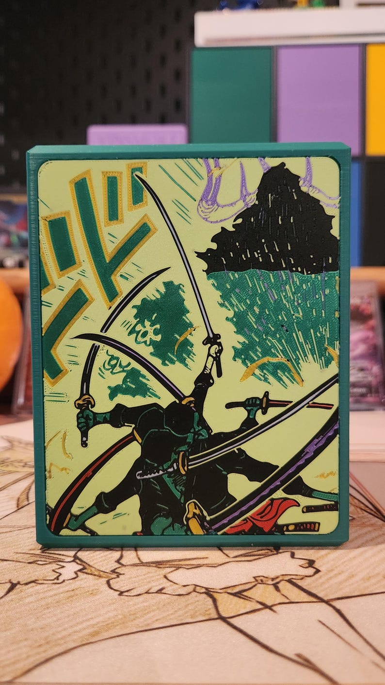 May include: A teal box featuring a dynamic illustration of sword-wielding figures in a battle scene. The artwork is in a Japanese woodblock print style, with a light green background and black and gold accents.