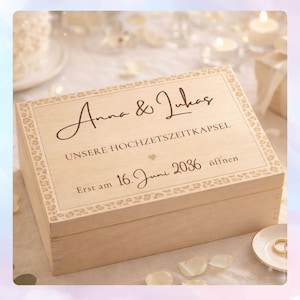 Könnte beinhalten: Eine hellfarbene Holzkiste mit dekorativem Leopardenmuster-Rand. Der Deckel trägt die Namen "Anna & Lukas" in eleganter Schrift, sowie Text und das Datum "16. Juni 2036". Ein Herzsymbol ist ebenfalls vorhanden. Die Kiste ist wahrscheinlich für eine Hochzeit.