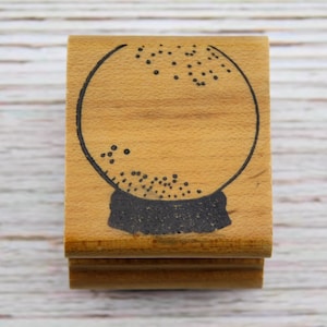 May include: A wooden stamp featuring a black outline of a crystal ball with dotted details. The stamp has a rectangular shape with a light brown wood grain finish, ideal for crafting and scrapbooking projects.
