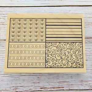 May include: A wooden stamp with four distinct patterned sections. The patterns include rows of tulip-like shapes, horizontal lines, circles, and swirling designs, all in black. The stamp is set against a light wood grain background.