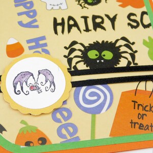 May include: Halloween-themed greeting card with a yellow background featuring a black spider, candy corn, and the words "HAIRY SC" and "Trick or treat". A circular sticker with purple bat-like creatures is also present.