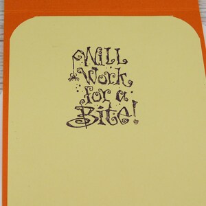 May include: A greeting card with an orange border and a light yellow interior. The text "Will Work for a Bite!" is written in a whimsical, dark brown font, with a spider graphic.