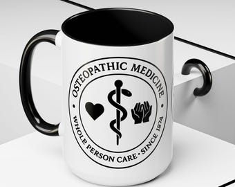 Könnte beinhalten: Weißer Keramikbecher mit schwarzem Innenraum und Griff. Der Becher hat ein rundes Emblem mit den Worten "Osteopathic Medicine" und "Whole Person Care Since 1874". Das Emblem enthält ein Herz, einen Stab mit einer Schlange und ein Paar Hände.