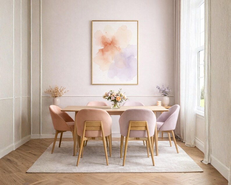 May include: A dining room scene featuring a light wood table surrounded by six velvet chairs in shades of pink and lavender. A framed abstract watercolor painting hangs on the wall. The room is decorated with flowers and a neutral rug.