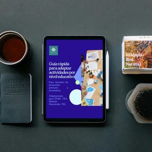 May include: An overhead shot of a workspace with a tablet displaying text in Spanish, a notebook, pen, coffee mug, and a coffee filter. The tablet has a white stylus next to it. A package of coffee beans is also visible.