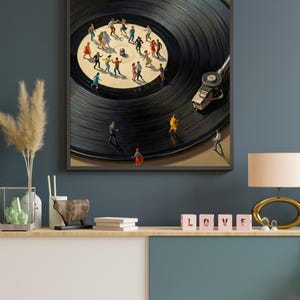 May include: A framed art print depicts a black vinyl record with miniature figures dancing on its surface. The artwork features a turntable and a beige background, creating a surreal and whimsical scene. The print is displayed on a wooden console.
