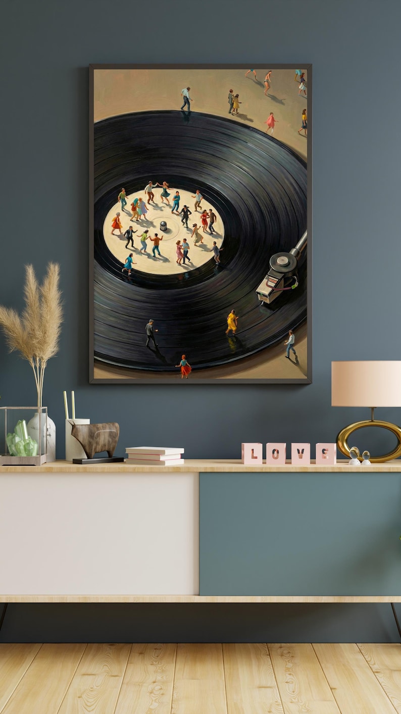 May include: A framed art print depicts a black vinyl record with miniature figures dancing on its surface. The artwork features a turntable and a beige background, creating a surreal and whimsical scene. The print is displayed on a wooden console.