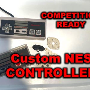May include: Two gray and black NES controllers with the text "Custom NES Controller" and "Competition Ready" in red. The controllers are accompanied by disassembled parts. The Nintendo logo is visible.