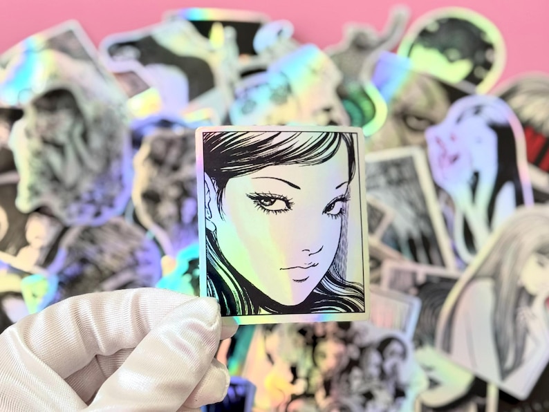 May include: A white ceramic mug with a black handle and the text "But First, Coffee" in a bold, black font. The mug is set against a blurred background, suggesting a cozy setting.