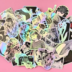 May include: A collection of holographic stickers featuring manga-style illustrations. The stickers depict various characters and scenes in black and white, with some accents of color. The stickers are arranged on a pink surface.