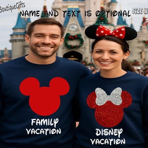 May include: Two navy blue sweatshirts with red Mickey Mouse and Minnie Mouse designs. One sweatshirt says "FAMILY VACATION" and the other says "DISNEY VACATION". The Minnie Mouse design has a silver glitter bow. The image is taken in front of a castle.