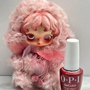 May include: A pink plush doll with a detailed face and a fluffy hood, next to a bottle of OPI GelColor nail polish. The nail polish bottle is red with white lettering and the text "I'M NOT REALLY A WAITRESS". The bottle contains 15 ml / 0.5 fl oz.