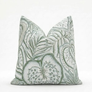May include: A decorative throw pillow with a botanical pattern. The pillow features a repeating design of large leaves and floral elements in shades of green and white. The pillow is square and appears to be made of fabric.