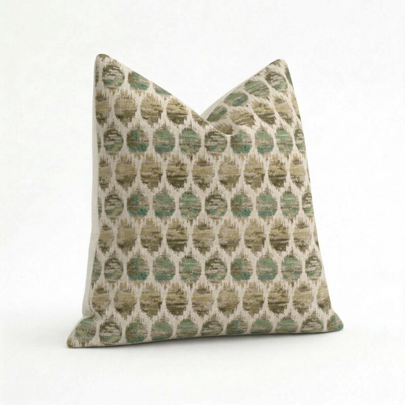 May include: A decorative pillow with a repeating pattern of teal and olive-green circles on a cream background. The pillow has a soft, textured appearance and is designed for home decor.