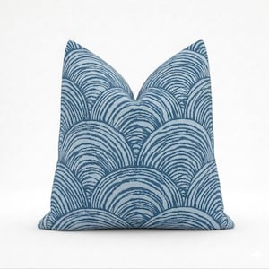 May include: A decorative throw pillow with a blue and white abstract pattern. The pillow features a repeating design of curved lines, creating a layered, wave-like effect. The pillow is square and appears to be made of fabric.