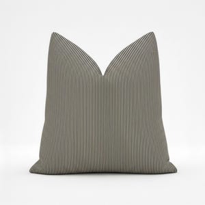 May include: A square decorative pillow with a vertical striped pattern in shades of gray and off-white. The pillow has a V-shaped top and is designed for home decor.