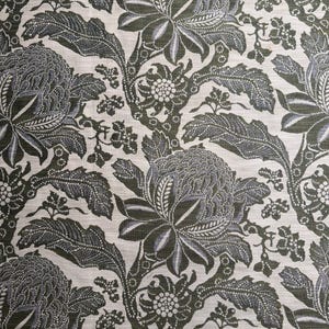 May include: Close-up of a fabric with a repeating floral pattern. The design features large, stylized flowers and leaves in shades of gray and dark green against a cream-colored background. The pattern has a vintage or botanical aesthetic.