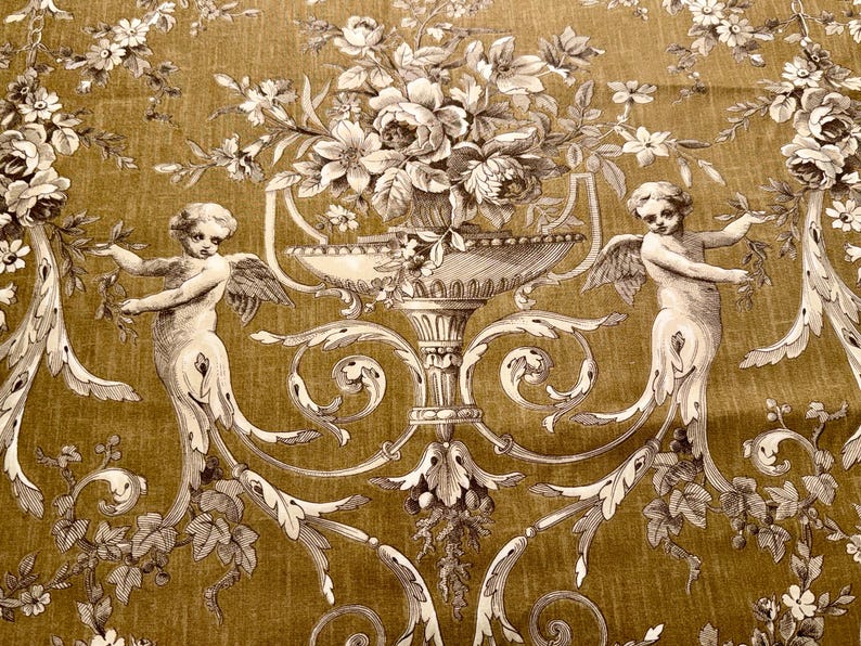 May include: A decorative fabric with a repeating pattern of cherubs, floral arrangements, and ornate scrollwork in shades of gold and cream. The design features detailed illustrations of angels with wings, holding floral garlands, and large urns filled with flowers.