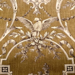 May include: A detailed pattern featuring a central bird with outstretched wings, surrounded by floral and ribbon motifs. The design is in shades of cream and brown, creating a vintage aesthetic. The background has a textured appearance.