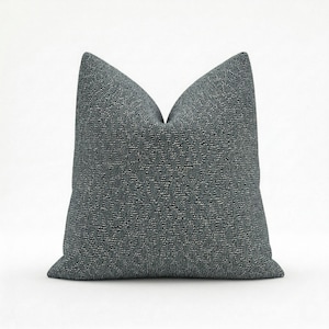 May include: A square, textured throw pillow in a dark gray color. The pillow has a woven pattern and a soft, inviting appearance. The pillow is designed for decorative use on a bed or sofa.