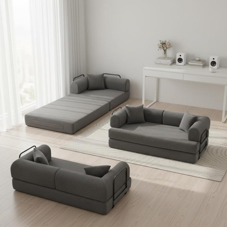 May include: Three modular gray fabric sofas with black metal frames and matching pillows. One sofa is fully extended, another is folded into a loveseat, and the third is a single seat. The sofas are on a light wood floor.