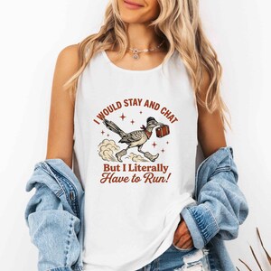 Peut inclure: Un débardeur blanc sans manches avec une illustration de roadrunner portant un bandana et des bottes, tenant une petite valise. Le texte indique : I WOULD STAY AND CHAT BUT I LITERALLY HAVE TO RUN ! Le motif inclut des étoiles et des nuages de poussière.