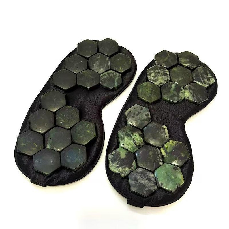 May include: Two black eye masks, each featuring a series of dark green, hexagonal stones. The stones are arranged in a pattern across the mask's surface. The masks are designed to cover the eyes.