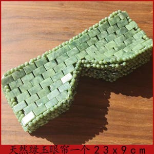 Puede incluir: Una m&aacute;scara de ojos de jade verde, rectangular, con un patr&oacute;n de ladrillos tejidos. Los bordes est&aacute;n bordeados con peque&ntilde;as cuentas redondas. La m&aacute;scara mide aproximadamente 23 cm por 9 cm.
