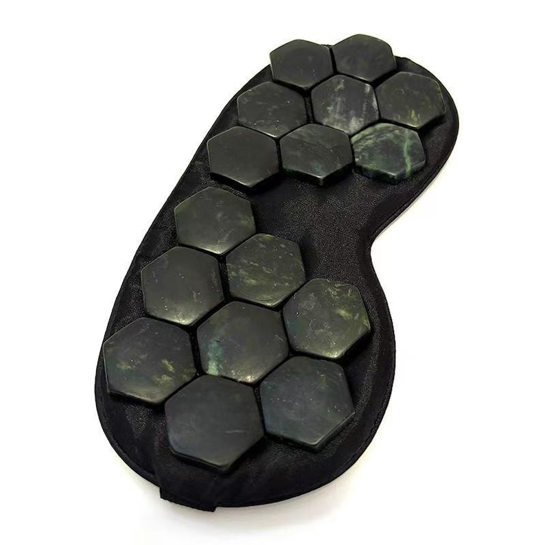 May include: A black eye mask featuring dark green, hexagonal jade stones. The stones are arranged across the front of the mask and have a mottled appearance. The mask is designed to cover the eyes, set against a white background.