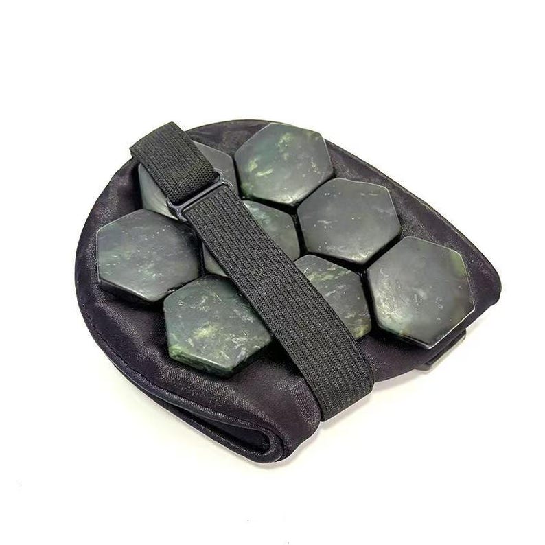 May include: A black jade stone massage tool with a black elastic strap. The tool features multiple hexagonal jade stones set in a black fabric pouch. The stones are a dark green colour.