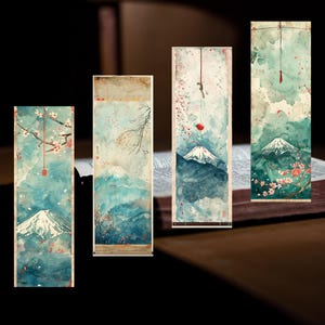 以下が含まれることがあります： 日本の風景を描いた水彩画のブックマーク4点セット。各ブックマークは、富士山、桜、青、緑、ピンクの色合いの穏やかな山の風景を特徴としています。長方形で、赤いアクセントが付いた紐が付いています。