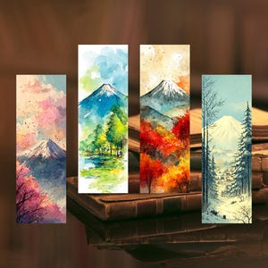 以下が含まれることがあります： 山岳風景を描いた水彩画のブックマーク4点セット。各ブックマークは異なる季節、春の花、夏の緑、秋の紅葉、冬の雪景色を描いています。ブックマークは長方形で、水彩画風の効果があります。
