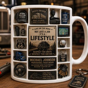 Peut inclure: Un mug en céramique blanche avec une grille d'icônes et de plaques en relief sur le thème du camion. Les éléments incluent un panneau Route 66, un semi-remorque bleu, un volant, un levier de vitesse et le texte Life on the Road et Michael Johnson.