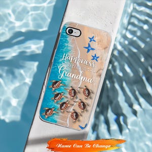 May include: A clear phone case featuring a beach scene with blue starfish and sea turtles. The case has the text "Happiness is Being a Grandma" and the words "Name Can Be Change" in orange.